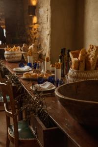 Table rustique dressée avec du pain artisanal, des paniers en osier, de l’huile d’olive et des verres à vin bleus, dans un cadre en pierre au charme méditerranéen.