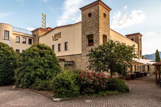 Elegante struttura in pietra immersa nel verde con giardino fiorito e vista sulle montagne.