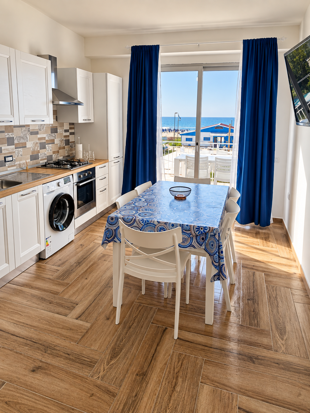 Cuisine moderne avec vue sur la mer avec table à manger et rideaux bleus.