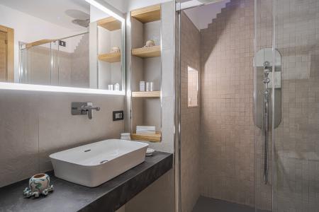 Modern bathroom with a countertop washbasin, backlit mirror, walk-in shower with stone-effect wall cladding, and wooden niches.