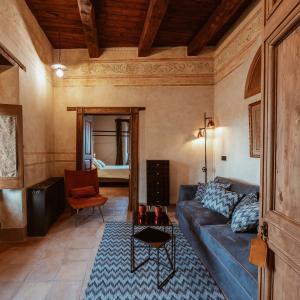 Rustikales Wohnzimmer mit freiliegenden Holzbalken, dekorierten Wänden, Terrakottaboden, blauem Sofa und Möbeln mit traditionellem Charme.
