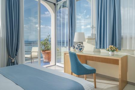 Bright room with sea views, light blue furnishings, and access to a balcony.