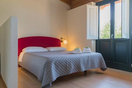 Chambre double lumineuse avec tête de lit rouge et porte française.