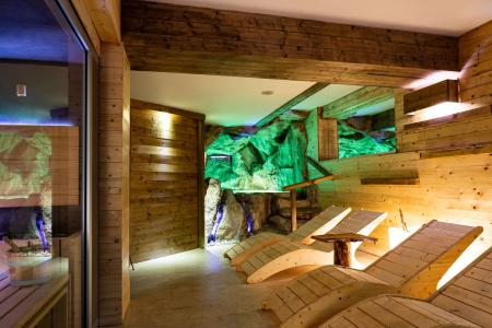 Area relax in legno con chaise longue e parete rocciosa illuminata.